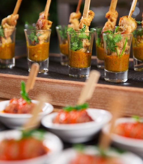 Delicious meat snacks with sauce on small plates and in shot glasses served on buffet table. Catering concept